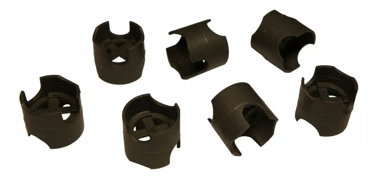 Siedem czarnych plastikowych podstawek pod zbrojenie na białym tle.