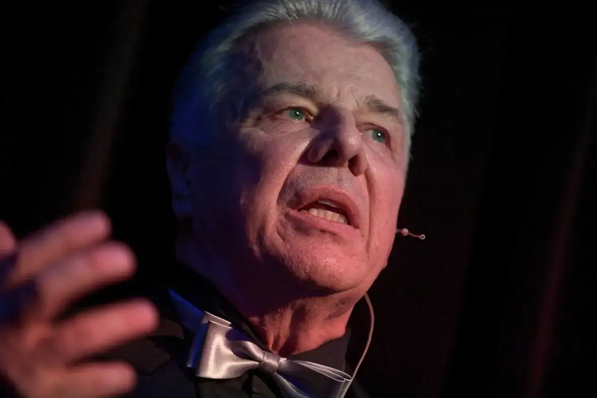 Emilian Kamiński, znany z wielu filmów, w eleganckim stroju z muszką, przemawia na scenie.