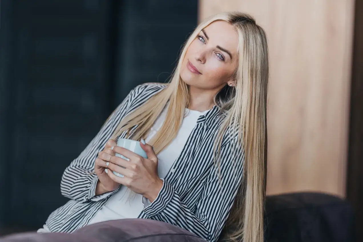 Blondynka z kubkiem w dłoniach, zamyślona, chce być sama.