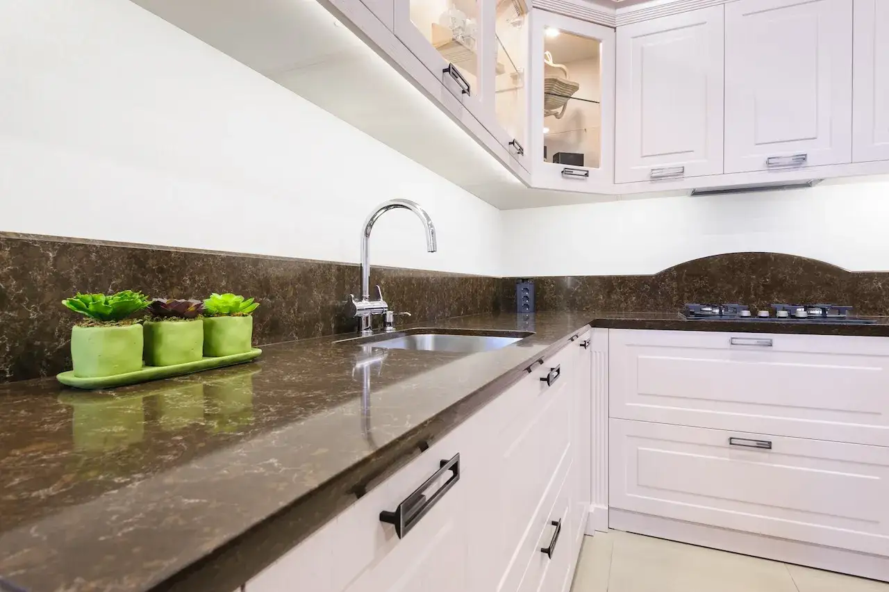 Nowoczesna kuchnia z białymi meblami, brązowym blatem i zlewozmywakiem.