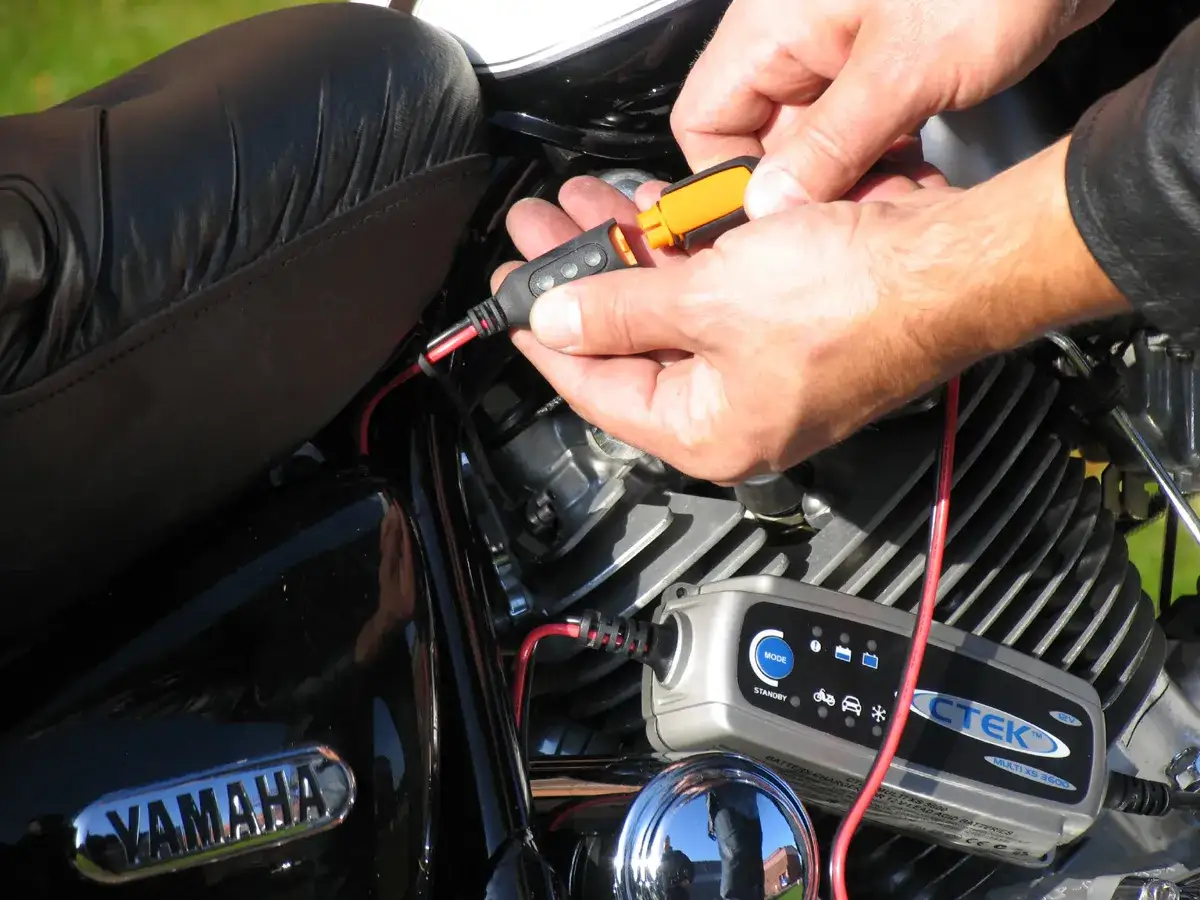 Ręce podłączają ładowarkę CTEK do akumulatora motocykla Yamaha.