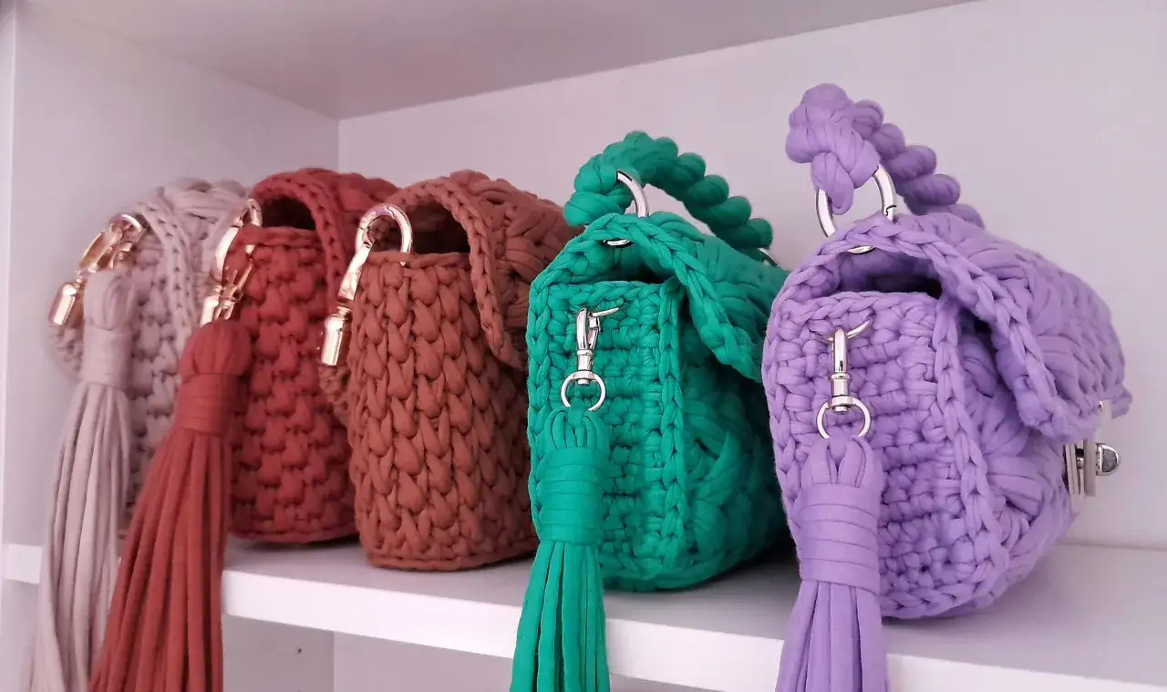 Pięć kolorowych torebek szydełkowych z frędzlami i metalowymi elementami. Inspiracja do stworzenia własnych torebek szydełkowych – schematy.