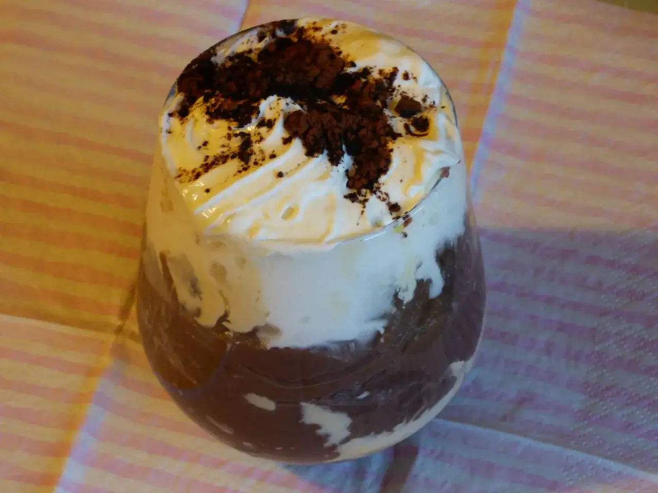 Pyszny deser z ugotowanego budyniu, bitej śmietany i kakao. Idealny pomysł na to, co można zrobić z ugotowanego budyniu.