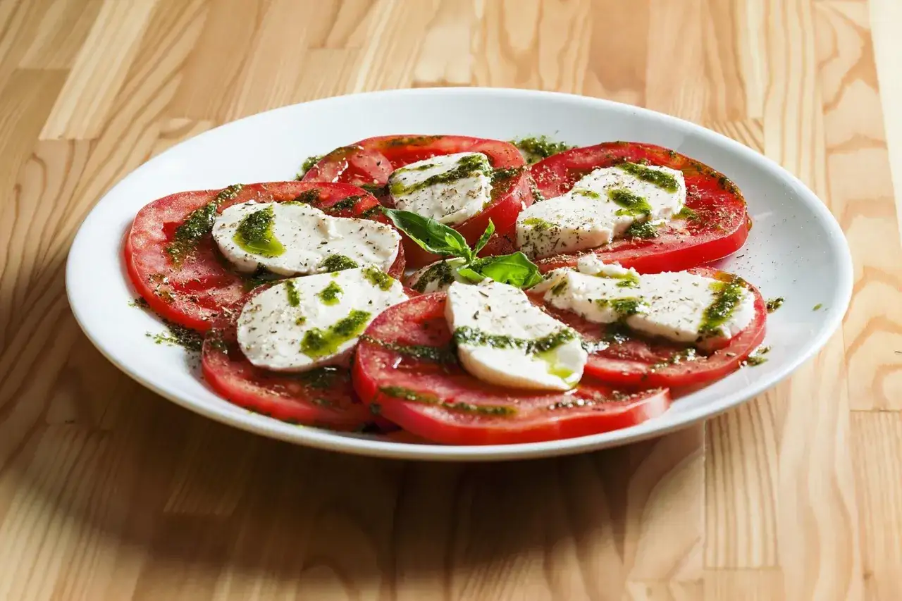 Sałatka caprese z pomidorów i mozzarelli, polana pesto. Idealne zdrowe przekąski na lato.