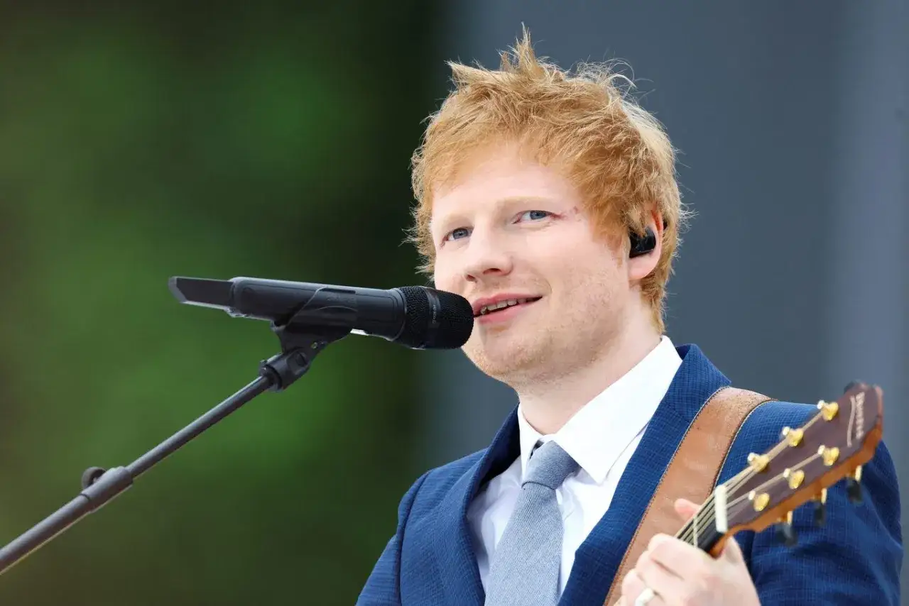 Ed Sheeran grający na gitarze i śpiewający do mikrofonu.