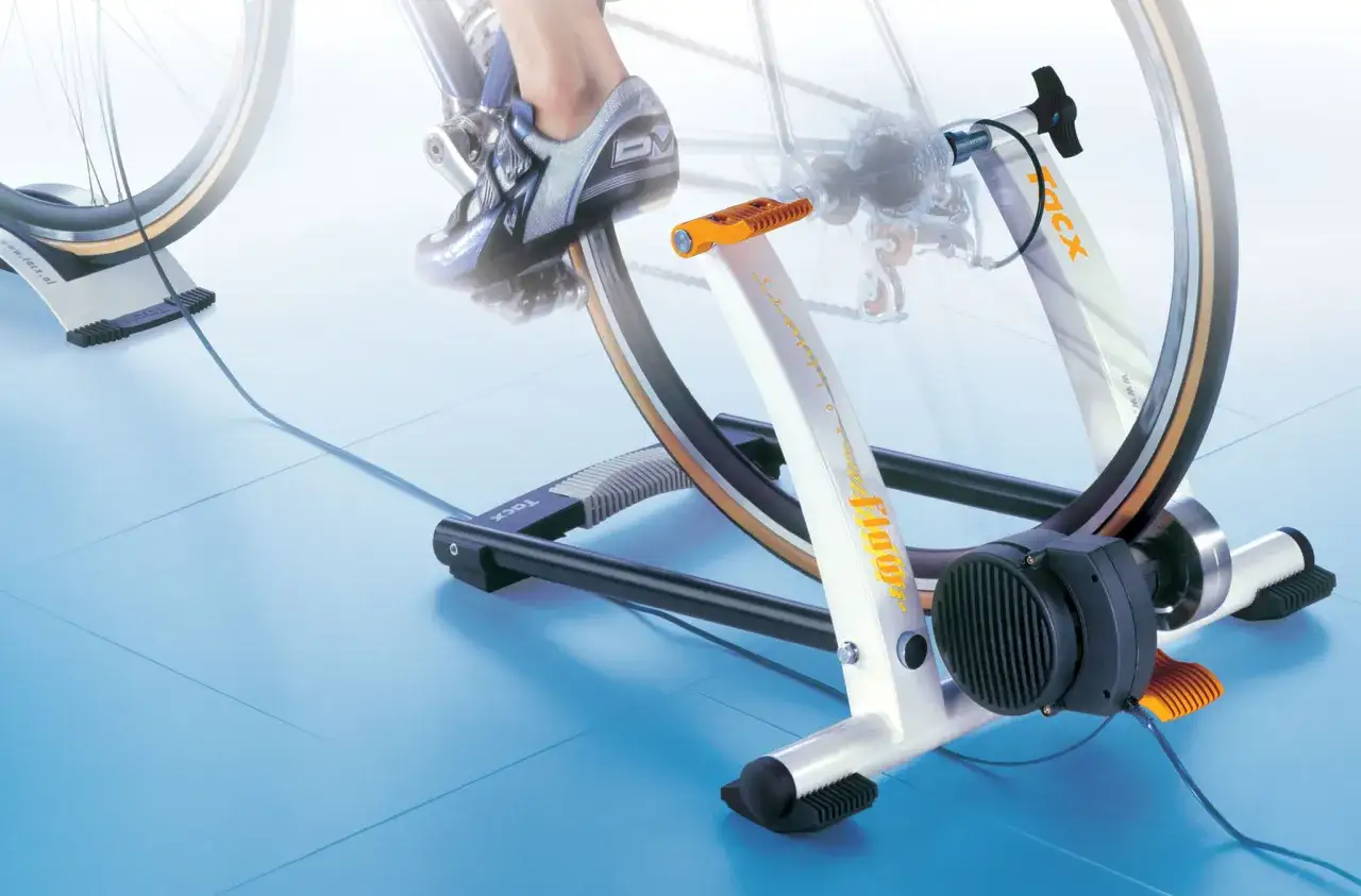 Trenażer rowerowy pozwala ćwiczyć jazdę na rowerze w domu. Widoczny rower jest zamontowany na urządzeniu, które symuluje jazdę.