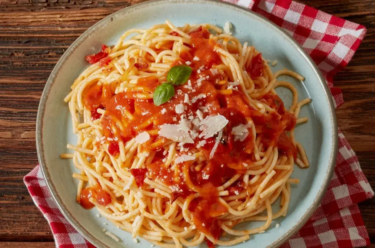 Pyszne spaghetti z sosem pomidorowym, parmezanem i listkiem bazylii. Idealne co do spaghetti na szybki obiad.