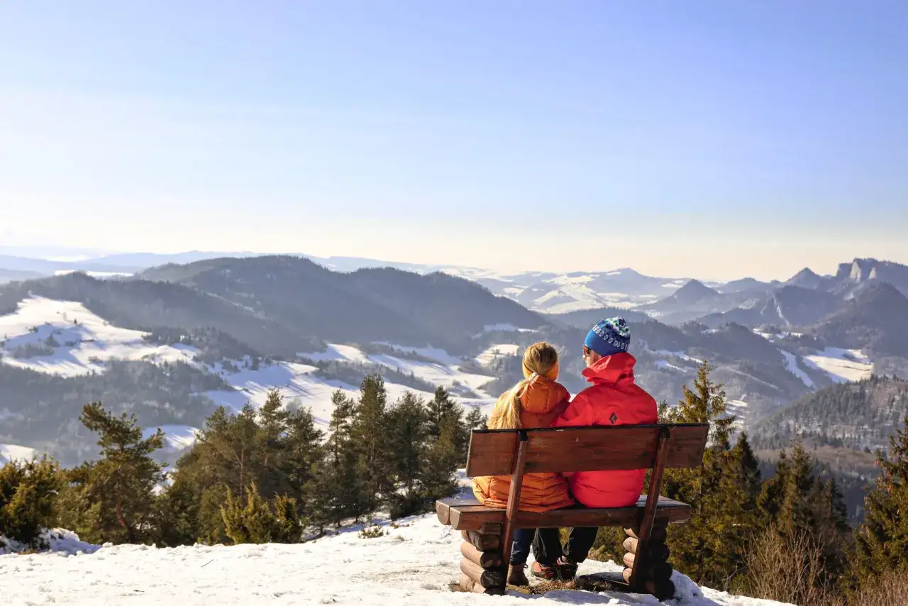 Para na ławce podziwia zimowy krajobraz Pienin z Wysokiego Wierchu.
