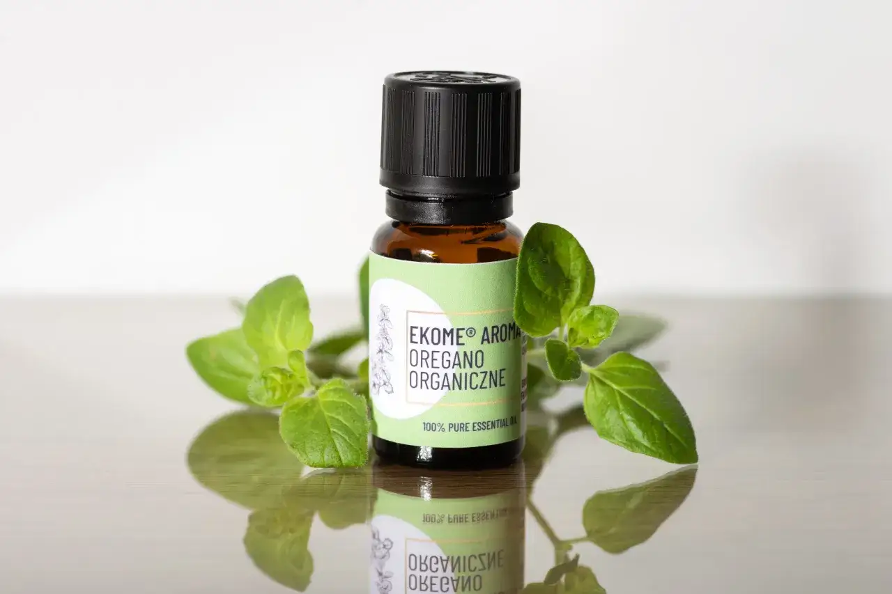Szukasz, gdzie kupić olejek z oregano? Na zdjęciu buteleczka z organicznym olejkiem z oregano, otoczona świeżymi gałązkami.