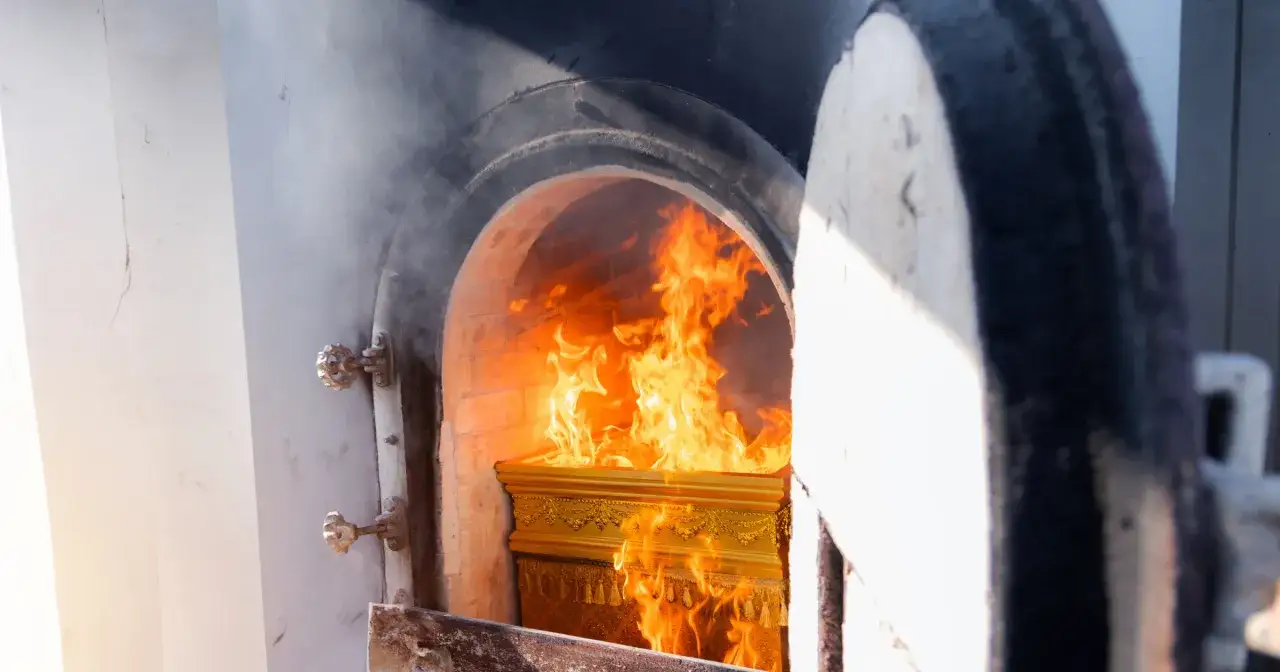 Złota trumna w płomieniach w piecu kremacyjnym.