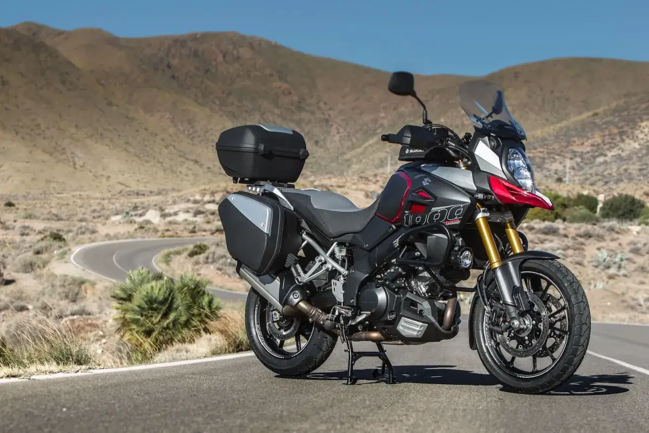 Suzuki DL 1000 V-Strom z kuframi, gotowy na przygodę na krętej drodze pośród pustynnych wzgórz.