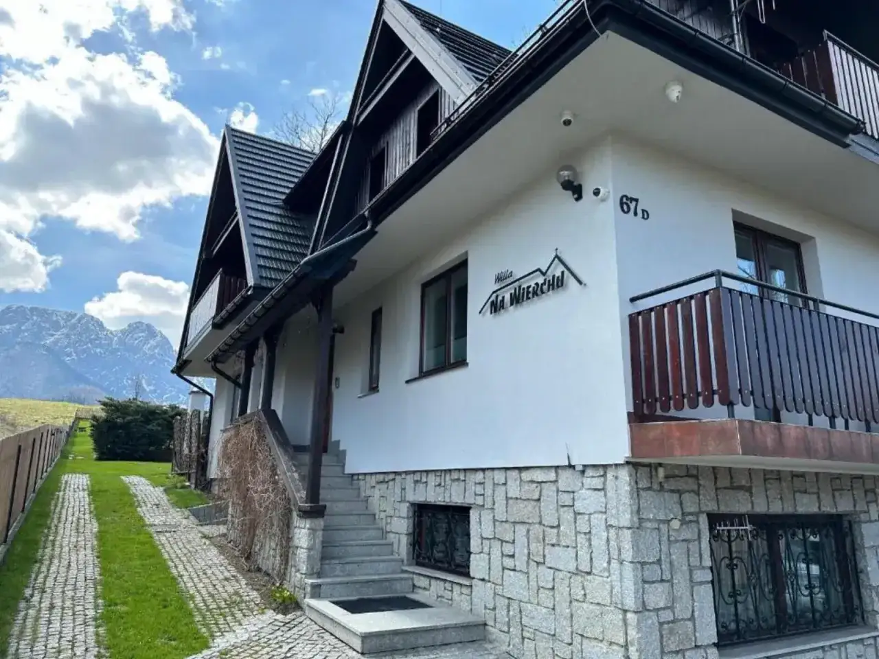 Willa Na Wierchu w Zakopanem, z kamienną podmurówką i drewnianymi elementami, wita gości pod malowniczymi Tatrami.