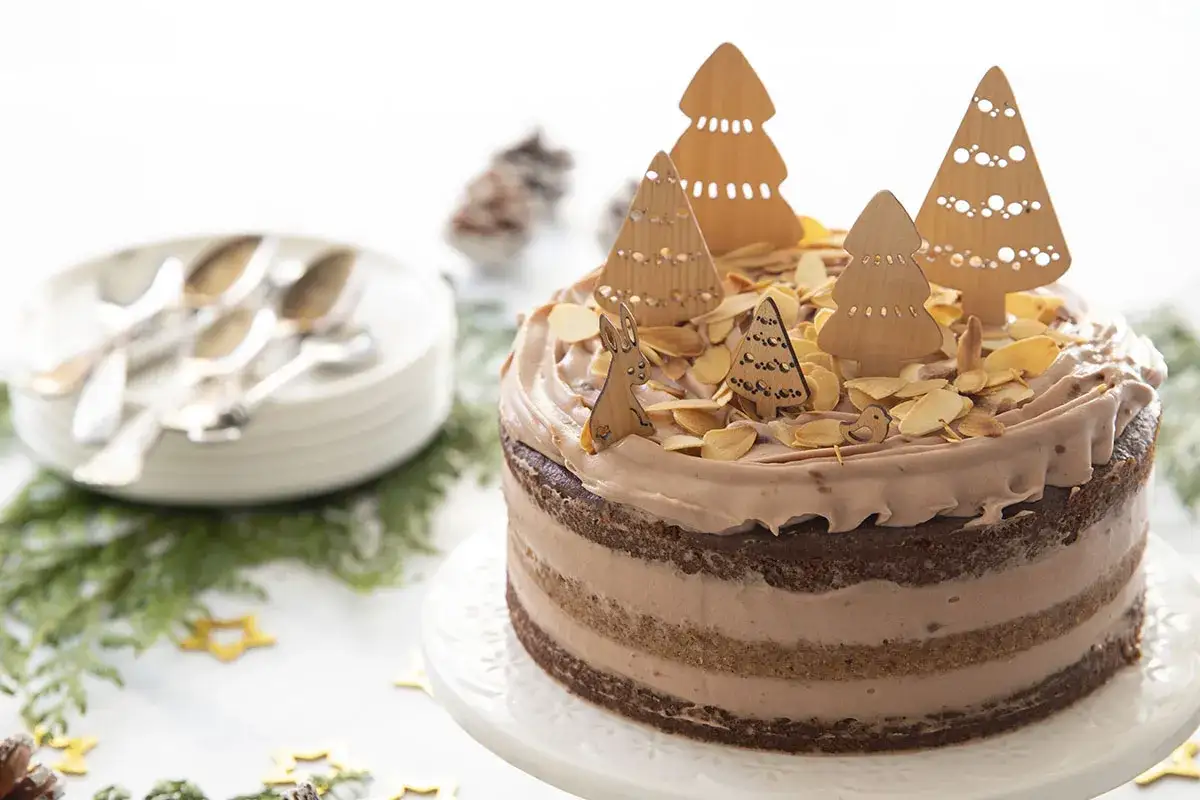 Gâteau au chocolat décoré d'arbres de Noël en bois, d'amandes effilées et d'un lapin.
