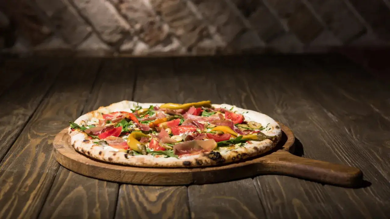 Pyszna pizza na drewnianej desce, idealna do pieczenia na kamieniu. Zobacz, jaki kamień do pizzy wybrać, by uzyskać chrupiący spód!