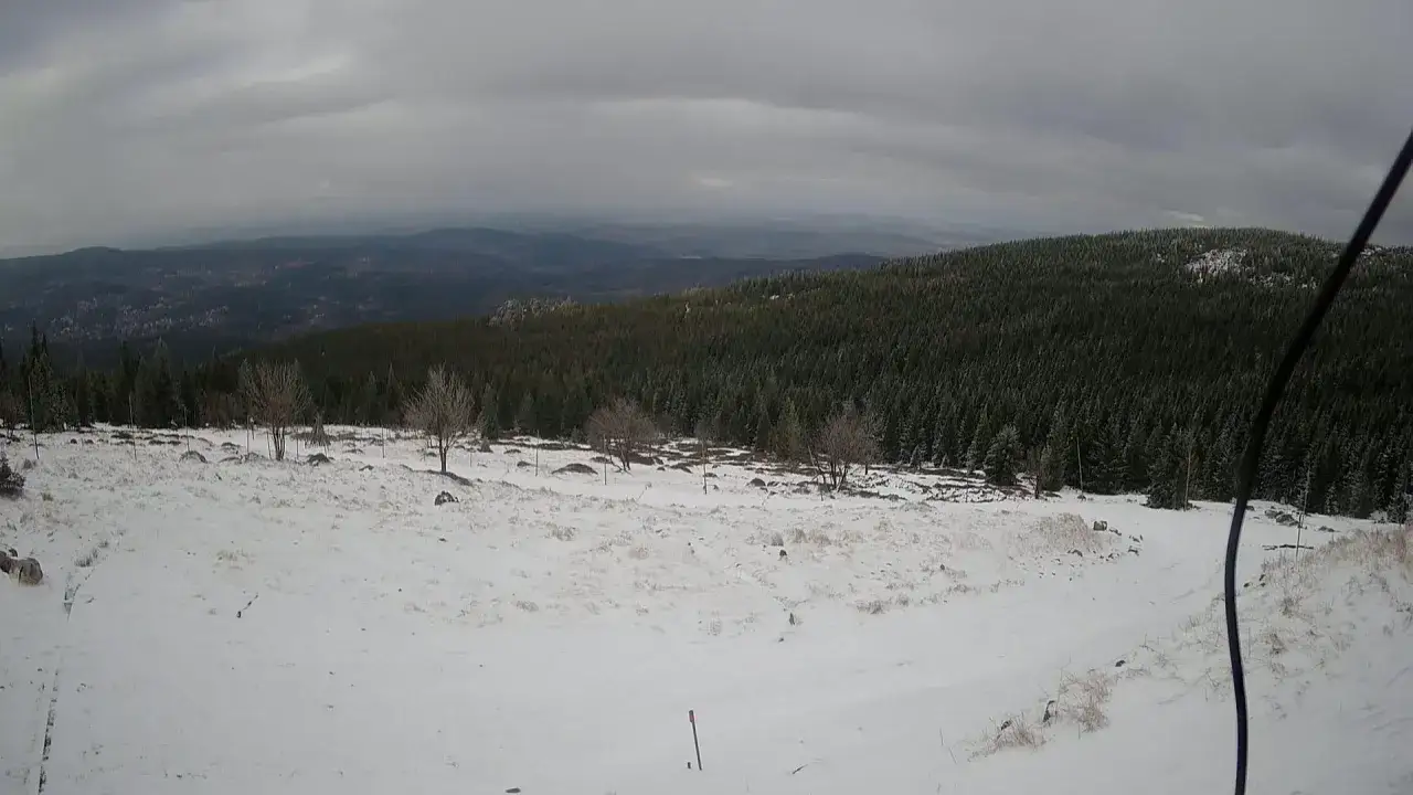 Zimowy krajobraz górski, pokryty śniegiem. W oddali las i mgliste wzgórza. Czy Śnieżka jest otwarta?