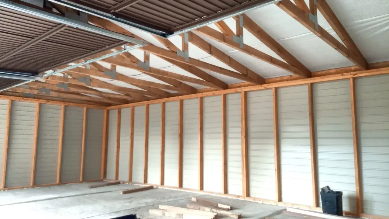 Szkielet garażu drewnianego z widocznymi belkami stropowymi i ścianami z płyt.