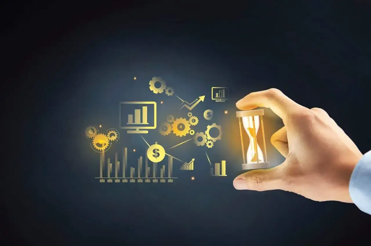 Dłoń trzyma klepsydrę na tle wykresów i ikon finansowych.