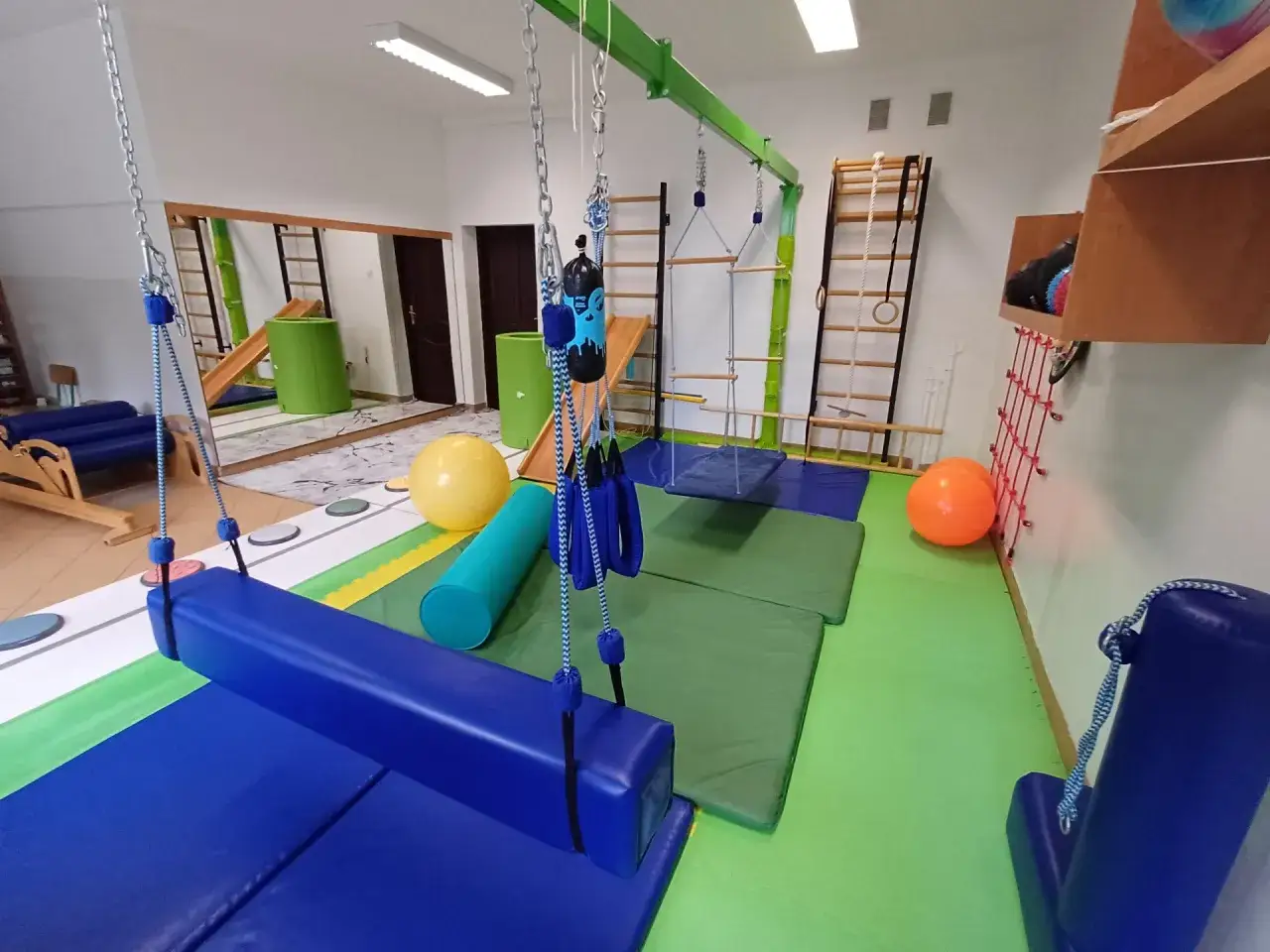 Sala terapeutyczna z huśtawkami, drabinkami, materacami i piłkami.