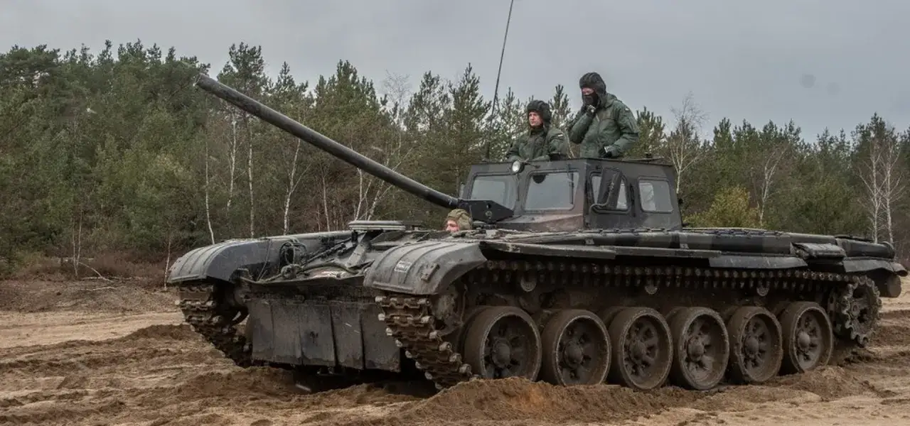 Szkolenie z zakresu jak zostać kierowcą czołgu. Trzech żołnierzy w wojskowych pojazdach, jeden z nich siedzi w otwartym włazie, dwóch innych w kabinie.