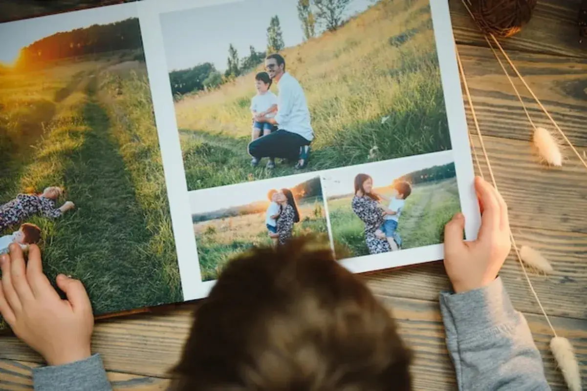 Dziecko przegląda fotoksiążkę z rodzinnymi zdjęciami. W Rossmannie można wywołać zdjęcia w różnych rozmiarach, idealnych do takich albumów.
