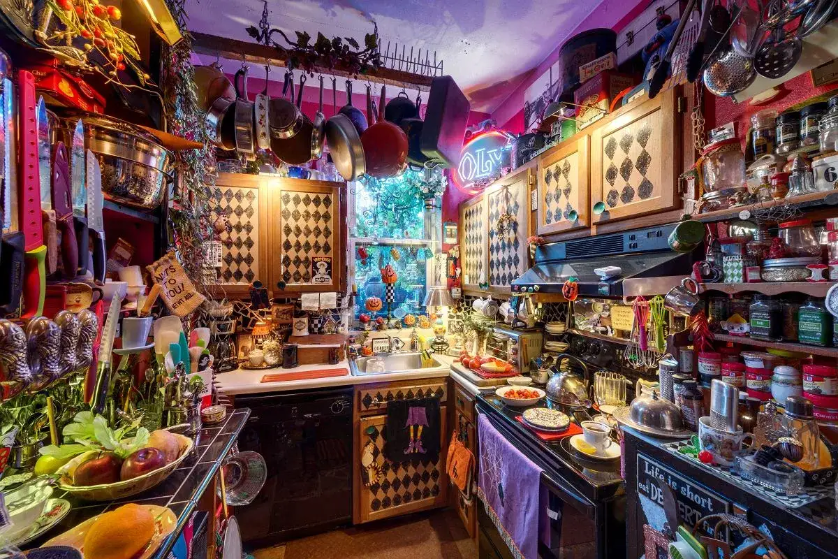 Kuchnia pełna przedmiotów, gdzie sztuka wyrzucania rzeczy jest wyzwaniem. Wiszące garnki, półki uginające się od słoików i dekoracji.