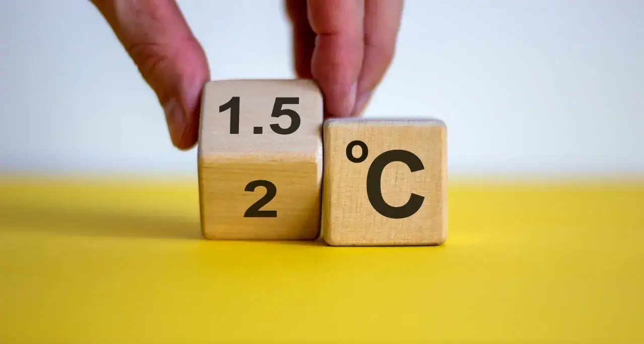 Dłoń obraca kostkę z "2" na "1.5", symbolizując cel paryskiego porozumienia klimatycznego.