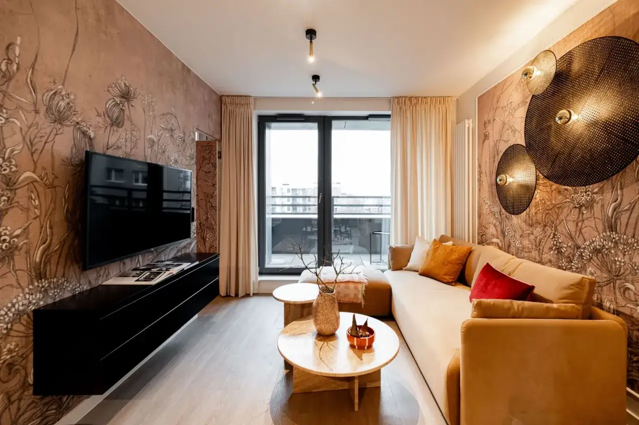 Nowoczesny salon z telewizorem w ścianie, ozdobionym tapetą z motywem roślinnym.