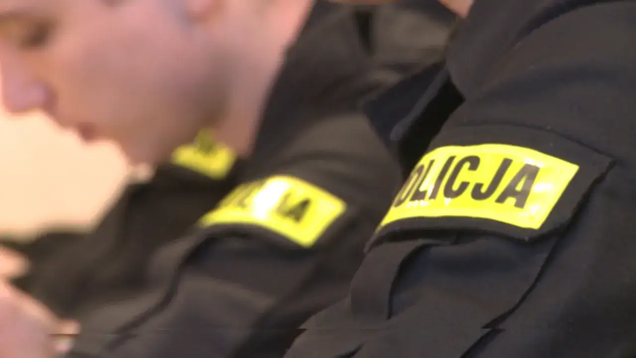 Zbliżenie na rękawy mundurów policyjnych z żółtymi naszywkami "POLICJA".