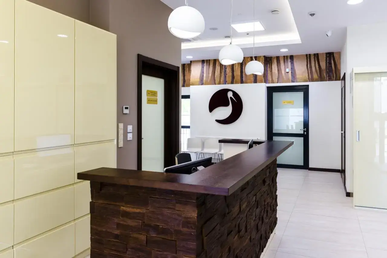 Nowoczesna recepcja kliniki Bocian Katowice. Elegancka lada, logo bociana i stylowe oświetlenie tworzą przyjazną atmosferę.