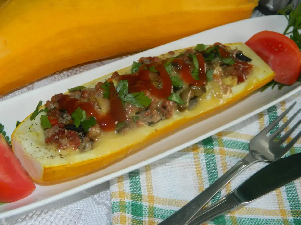 Pół cukinii faszerowanej mięsem mielonym i pieczarkami, polanej keczupem i posypanej natką pietruszki.