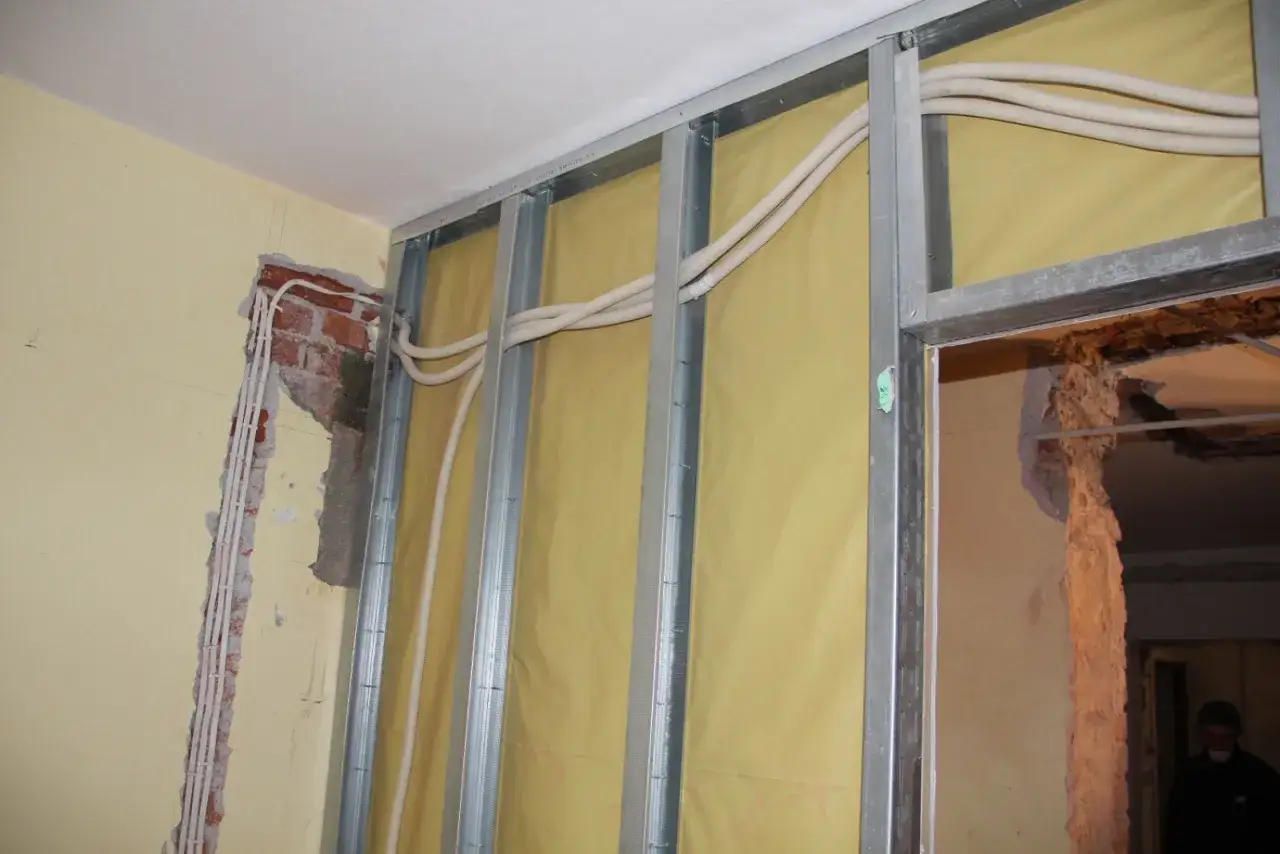 Trwa wymiana instalacji elektrycznej w mieszkaniu. Widać metalowy stelaż, żółtą membranę i nowe przewody elektryczne w peszlach.