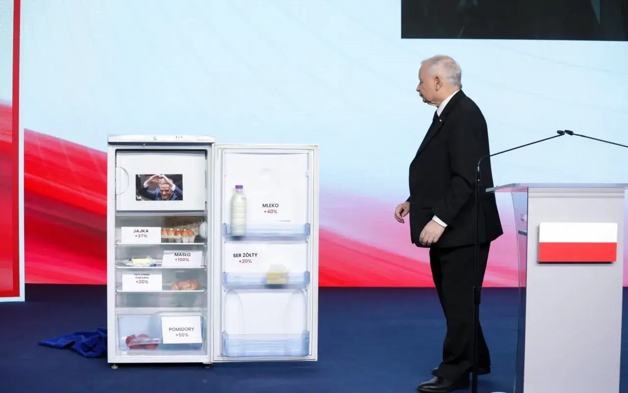 Otwarta lodówka z produktami i etykietami wzrostu cen, obok polityk. Ilustracja programu gospodarczego PiS a realia inflacji.
