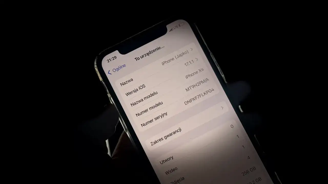 Ekran iPhone'a z widocznymi informacjami o urządzeniu, w tym wersją iOS i modelem.