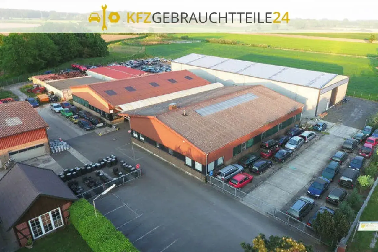 Luftaufnahme eines Autoteile-Lagers mit Gebäuden und vielen Autos.