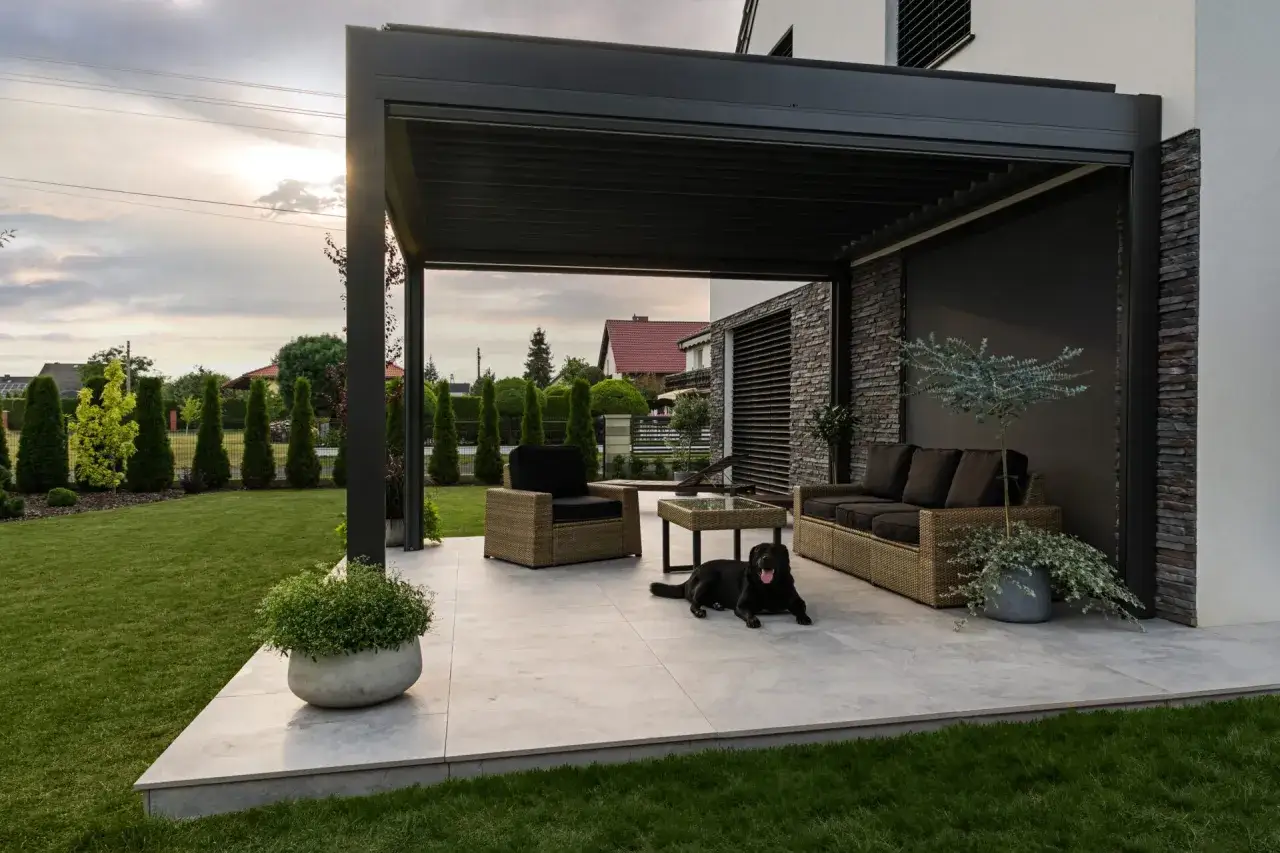 Nowoczesna pergola z zacienieniem, meble wypoczynkowe i pies. Idealne miejsce do relaksu, zastanawiasz się, czym zabezpieczyć pergole?