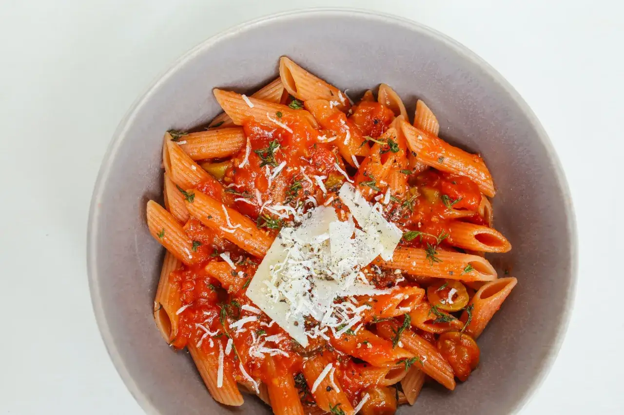 Penne w sosie pomidorowym z ziołami i parmezanem. Idealny przepis na zdrowy makaron, który zachwyci smakiem.