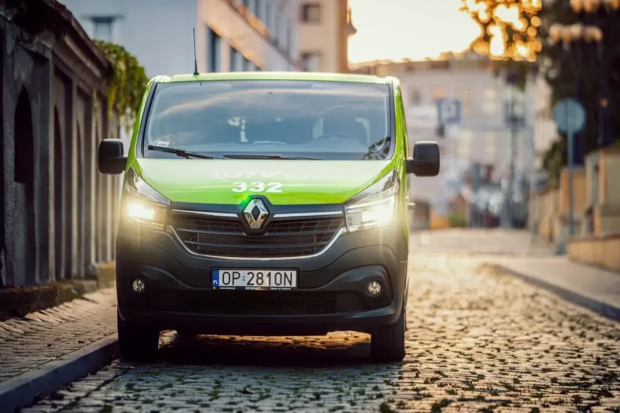 Zielony bus GTV BUS 332 na brukowanej ulicy. Sprawdź, ile kosztuje bus z adresu pod adres.