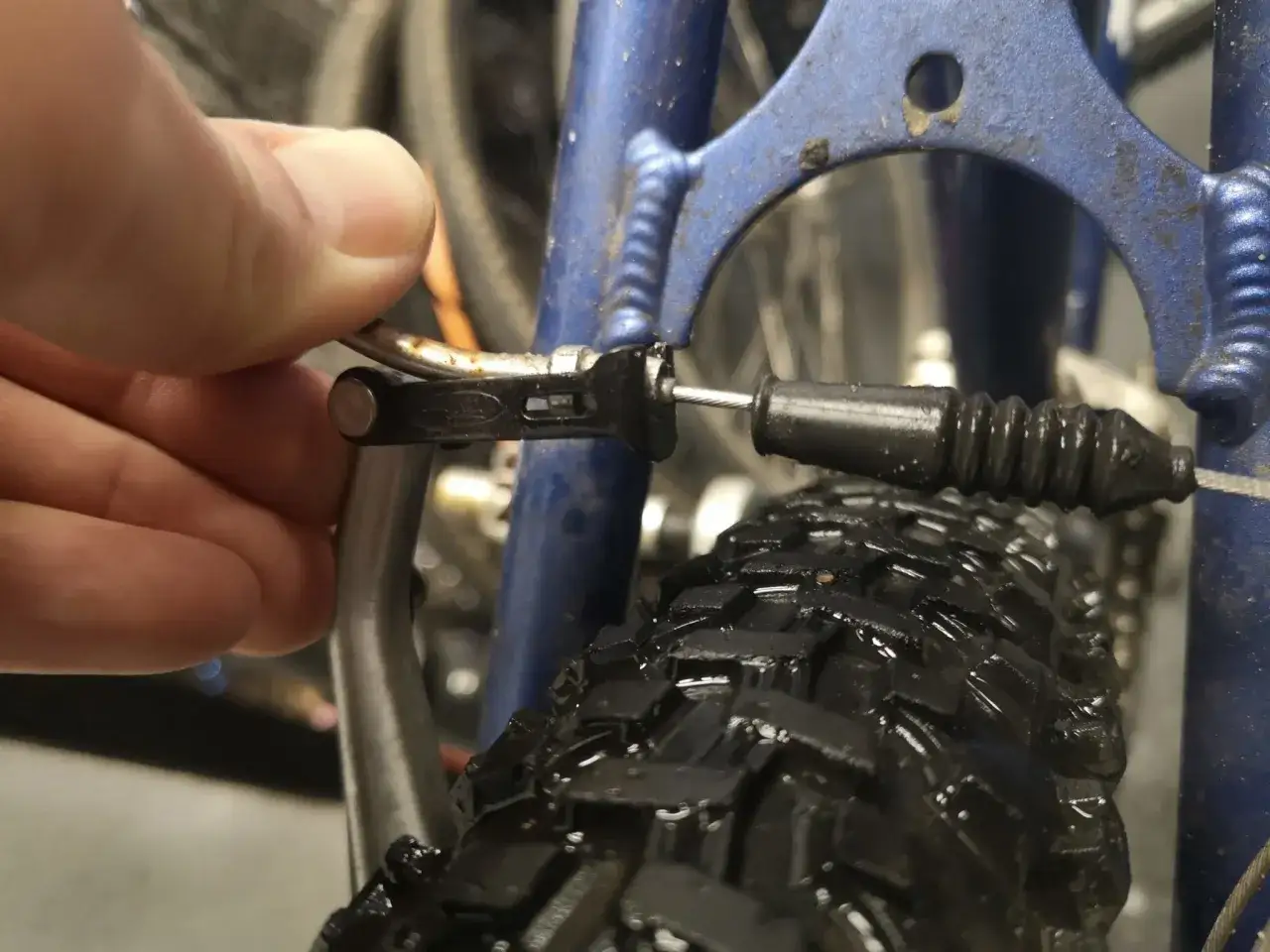 Dłoń reguluje linkę hamulca v-brake, by wyeliminować piszczące hamulce w rowerze.