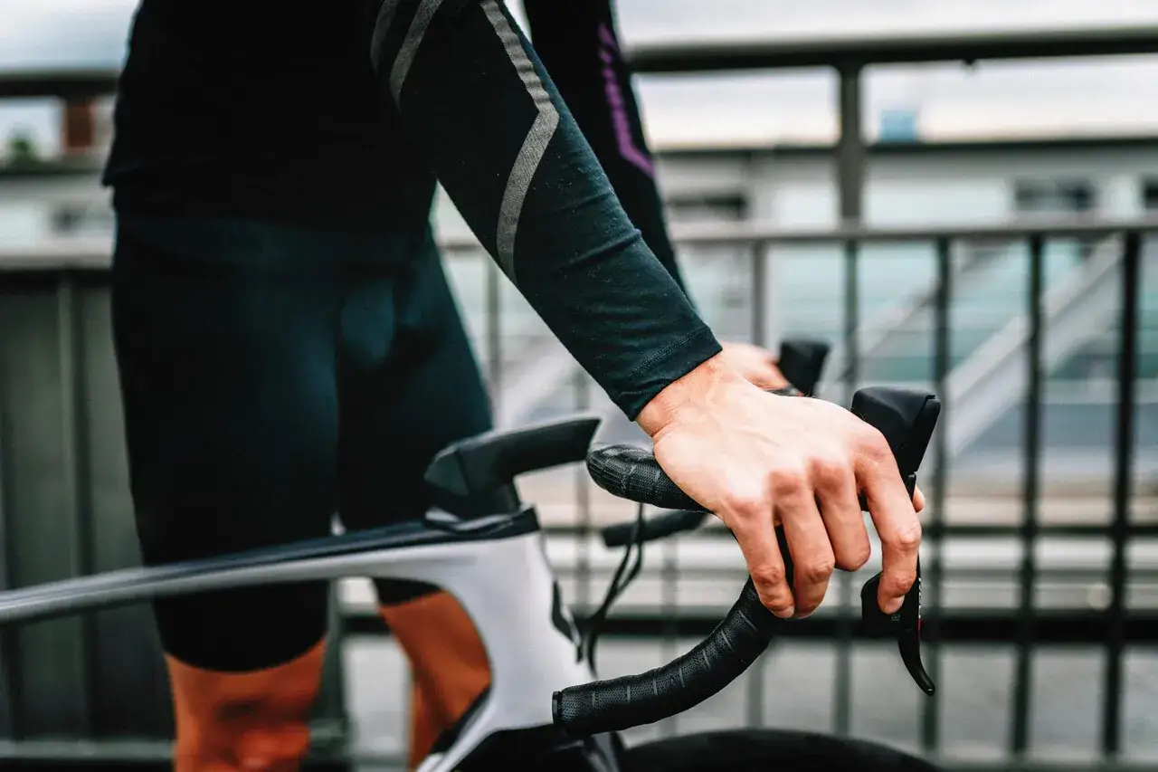 Rowerzysta z silnym bólem ud po jeździe na rowerze, trzymający kierownicę.