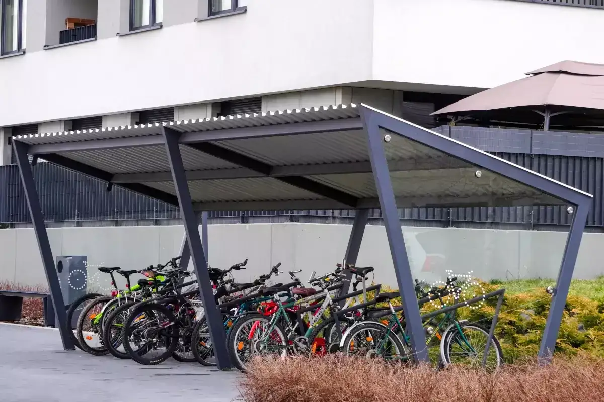 Rzędy rowerów czekają na swoich właścicieli pod nowoczesną wiatą. Bezpieczne przechowywanie roweru na dworze to wygoda i ochrona przed deszczem.