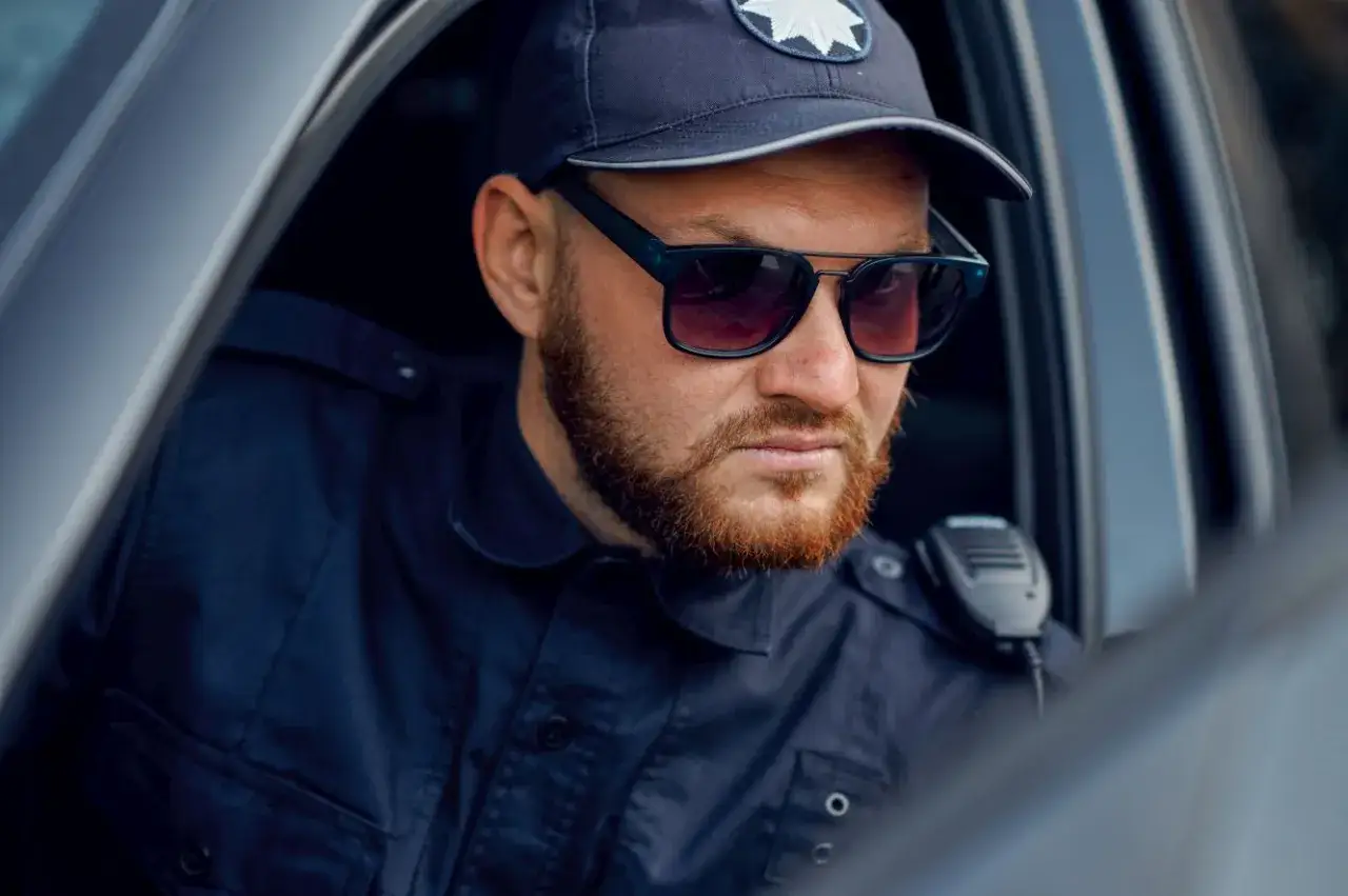 Policjant w okularach przeciwsłonecznych i czapce, gotowy do akcji. Marzysz, jak zostać policjantem kryminalnym?