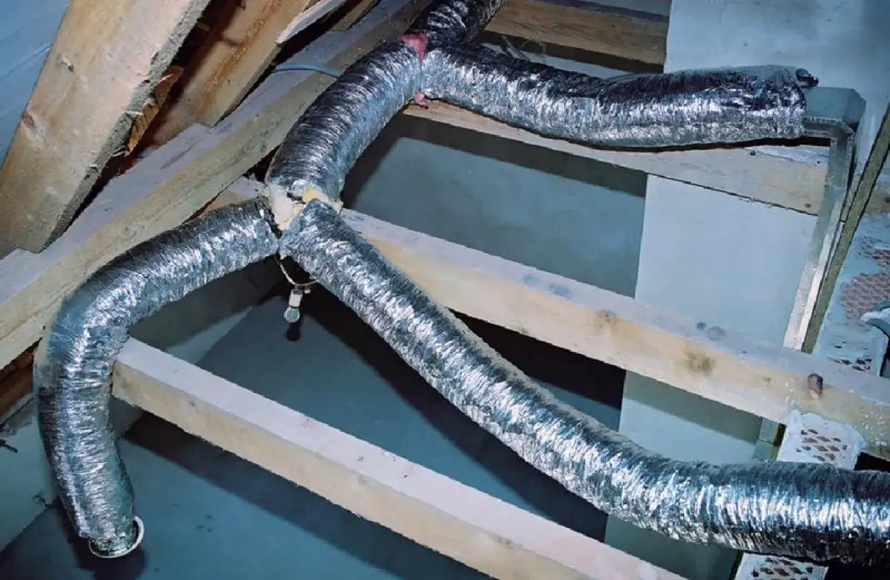 System rozprowadzenia ciepła z kominka: elastyczne, aluminiowe rury wentylacyjne prowadzone przez drewnianą konstrukcję poddasza.