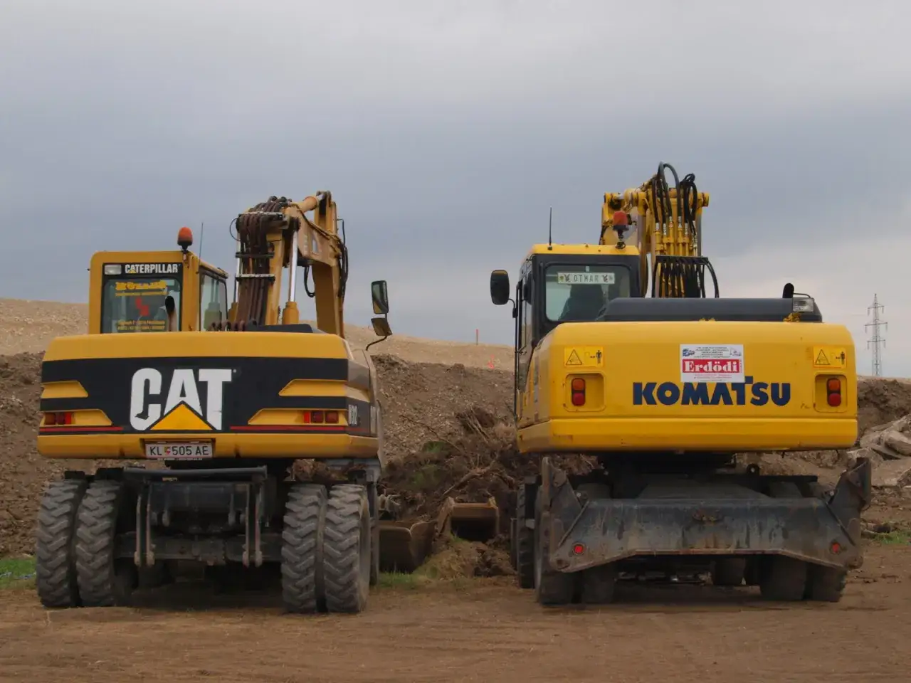 Dwie żółte koparki, CAT i Komatsu, stoją obok siebie. Czy koparkę się rejestruje?