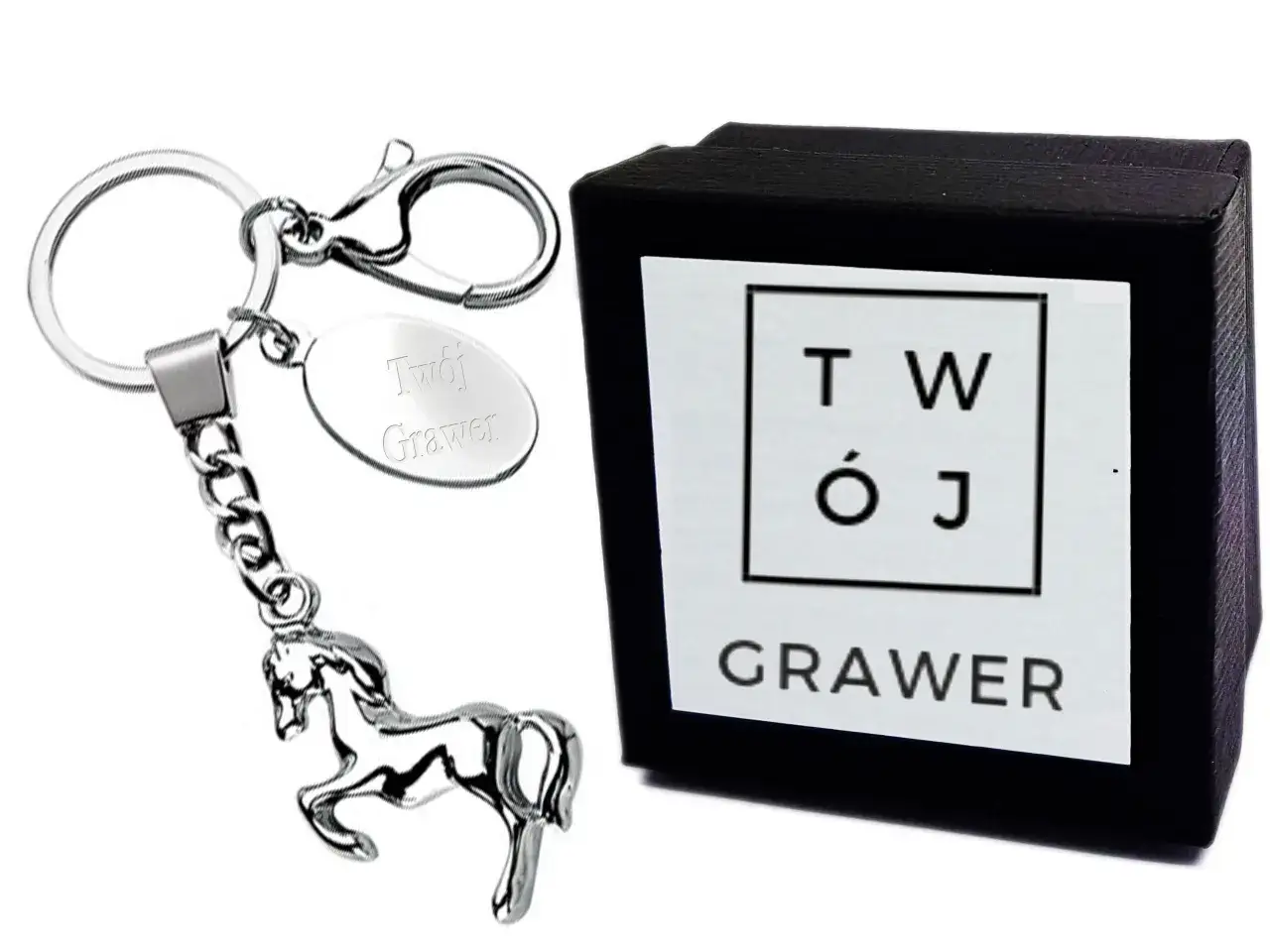 Eleganckie gadżety z koniem: brelok z metalowym koniem i owalną zawieszką z grawerem "Twój Grawer" obok czarnego pudełka z logo "TWÓJ GRAWER".