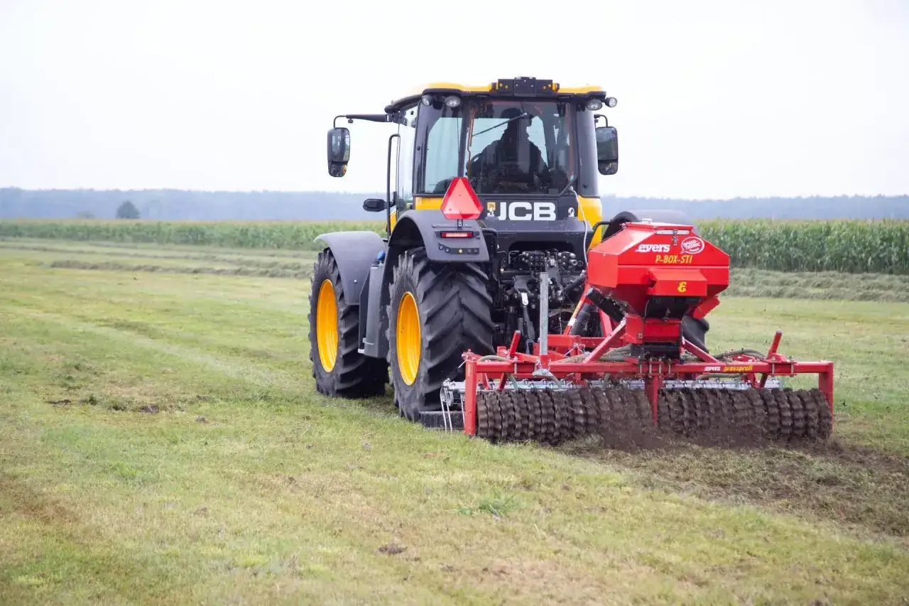 Ciągnik JCB z rozsiewaczem nawozu na polu.