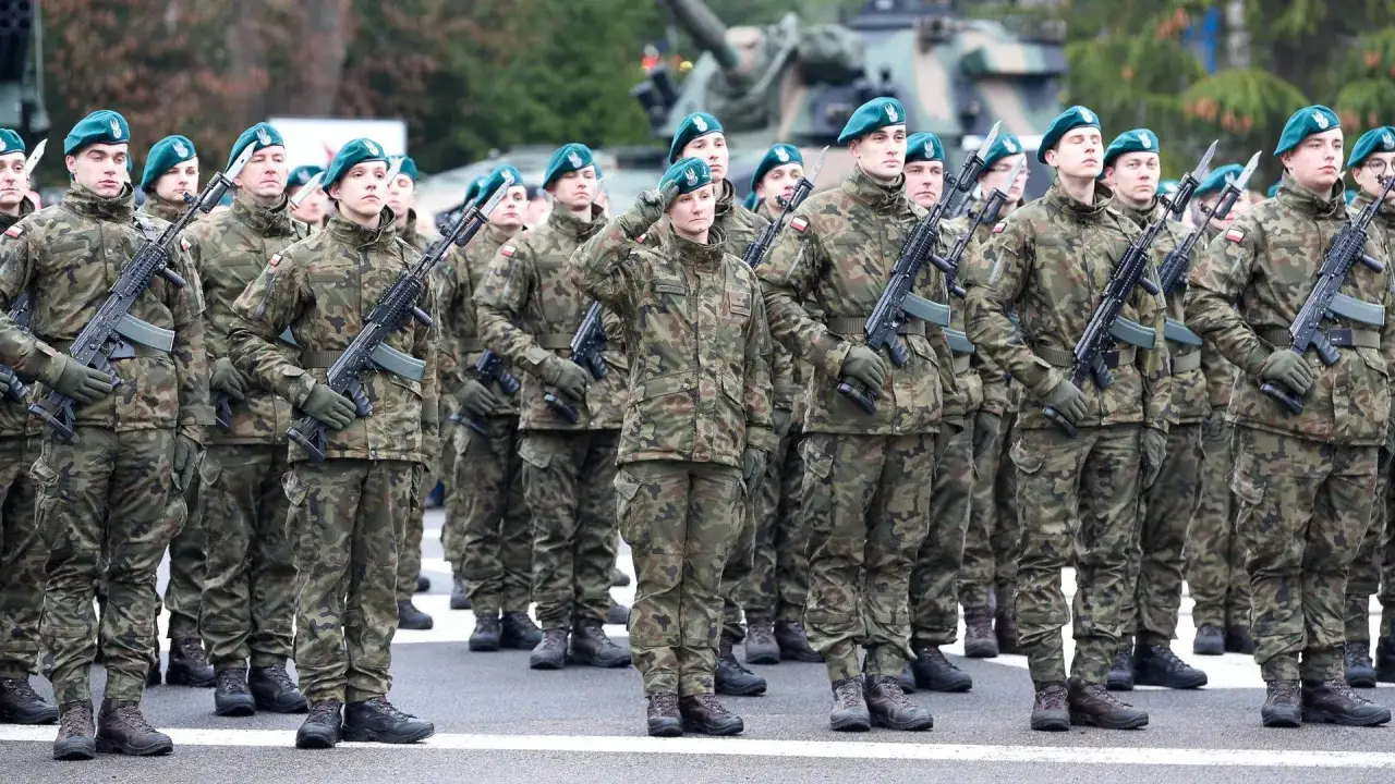 Żołnierze w mundurach i zielonych beretach stoją w szeregu, trzymając broń.