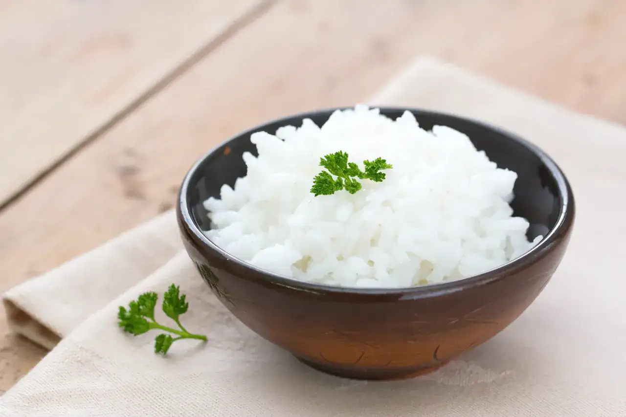 Miseczka z idealnie ugotowanym ryżem, ozdobiona gałązką pietruszki.
