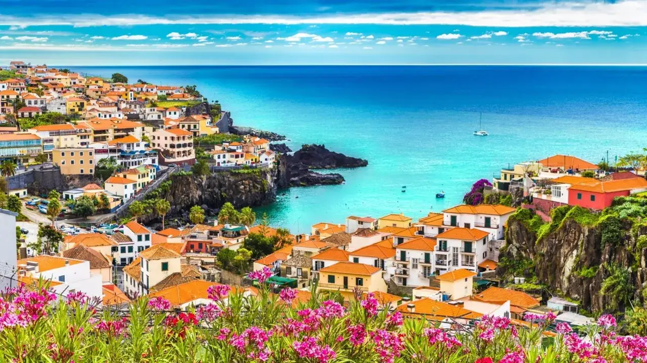 Wspaniała madera pogoda w październiku. Kolorowe domy na klifie, turkusowe morze i kwitnące kwiaty tworzą rajski widok.