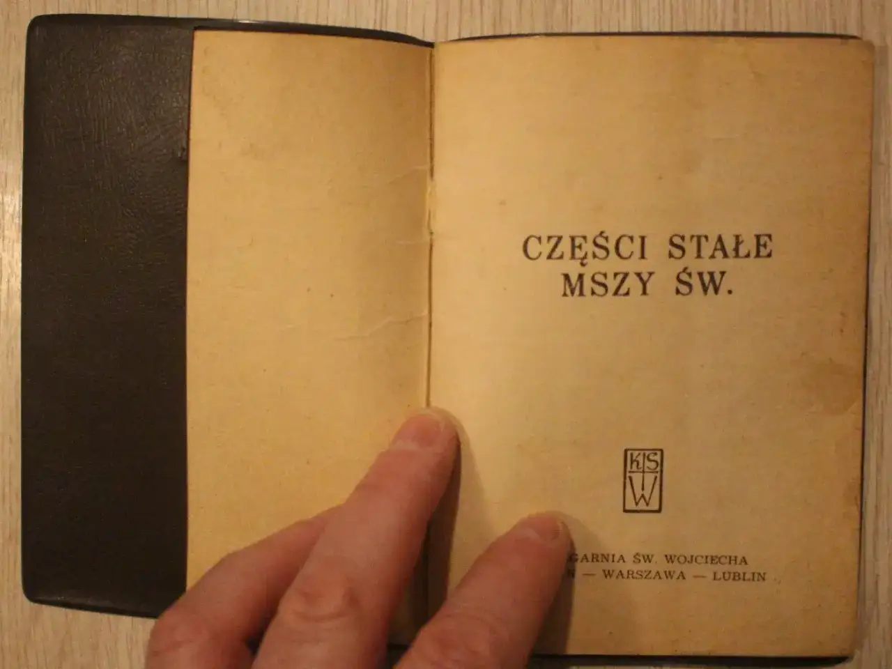 Otwarta książeczka z napisem "CZĘŚCI STAŁE MSZY ŚW.". Widoczny fragment okładki i strony z tekstem.