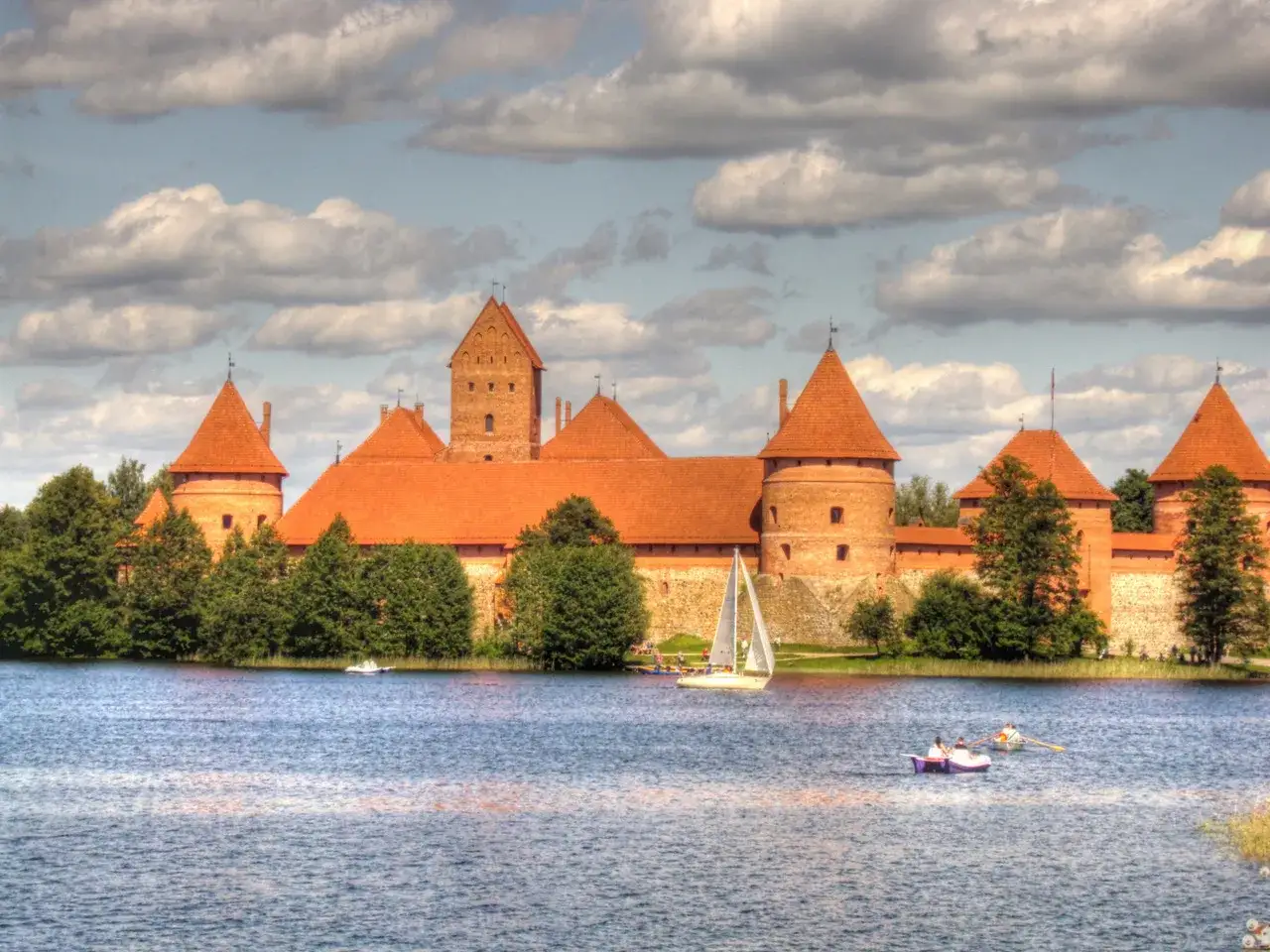 Zamek w Trokach, symbol tego, z czego słynie Litwa, na tle jeziora z żaglówkami.